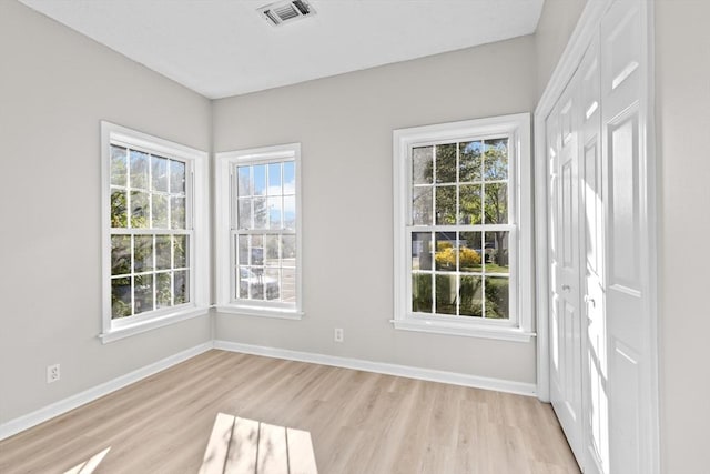 empty room with visible vents, light wood-style floors, and baseboards
