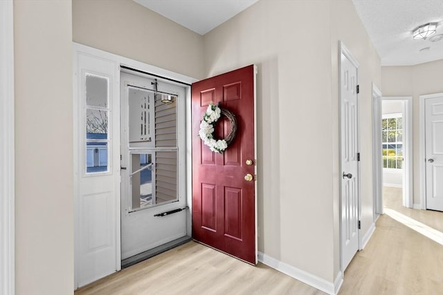 foyer entrance featuring baseboards and light wood finished floors