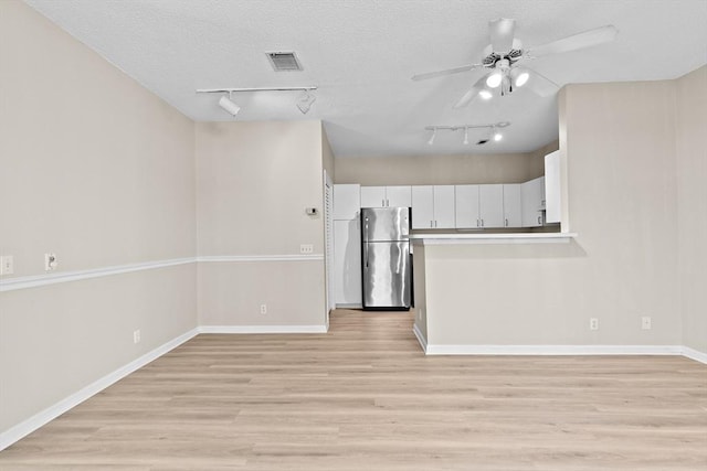 kitchen featuring a ceiling fan, visible vents, freestanding refrigerator, light wood finished floors, and white cabinetry