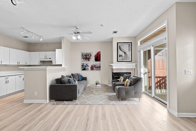 living room with light wood-style floors, a textured ceiling, and visible vents
