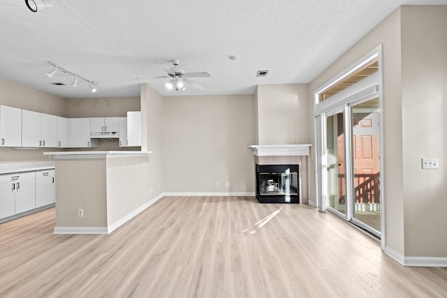 unfurnished living room with light wood-style floors, a textured ceiling, and visible vents