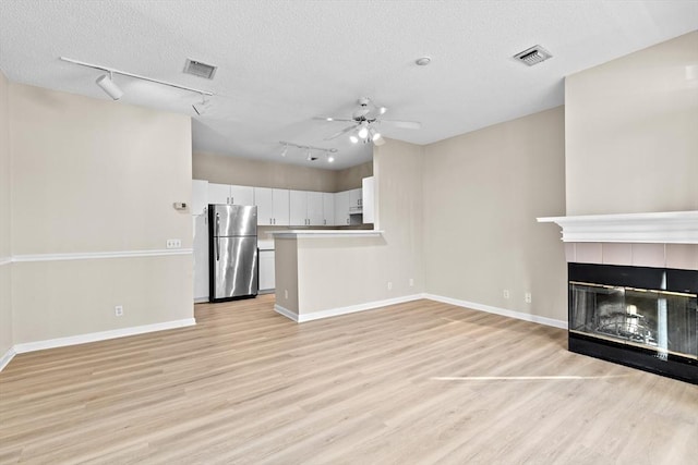 unfurnished living room with ceiling fan, track lighting, light wood finished floors, baseboards, and visible vents