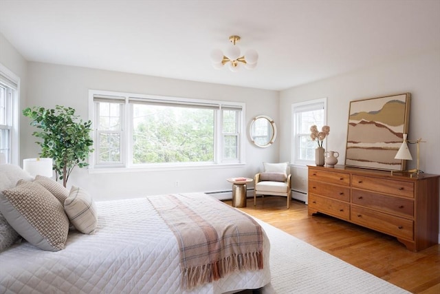bedroom featuring wood finished floors and a baseboard radiator