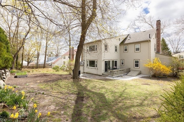 back of property featuring a lawn, a wooden deck, and a chimney