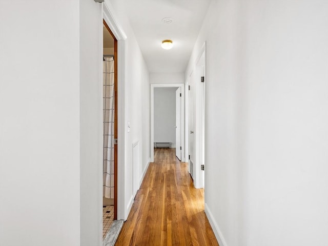 hallway with light hardwood / wood-style flooring and a baseboard heating unit