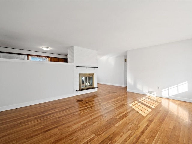 unfurnished living room featuring hardwood / wood-style floors and a brick fireplace