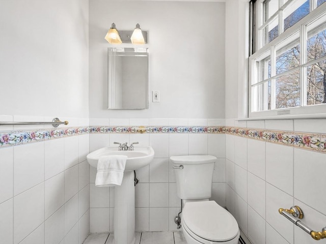 bathroom with toilet and tile walls