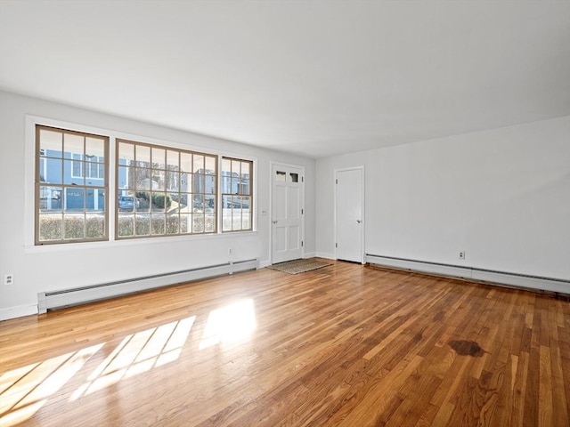 empty room featuring baseboard heating and hardwood / wood-style floors