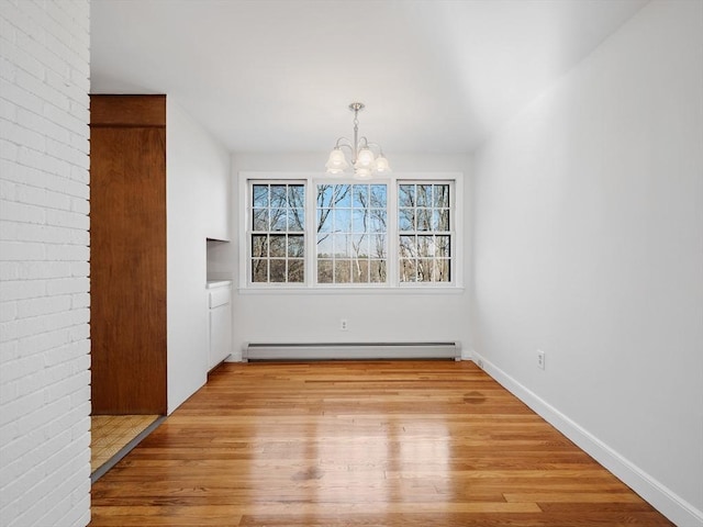 unfurnished dining area featuring a chandelier, a baseboard radiator, and light wood-type flooring