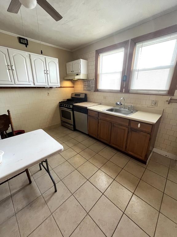 23 Highland Rd, Somerville, MA 02144 - kitchen with appliances with stainless steel finishes, under cabinet range hood, light tile patterned floors, light countertops, and white cabinets