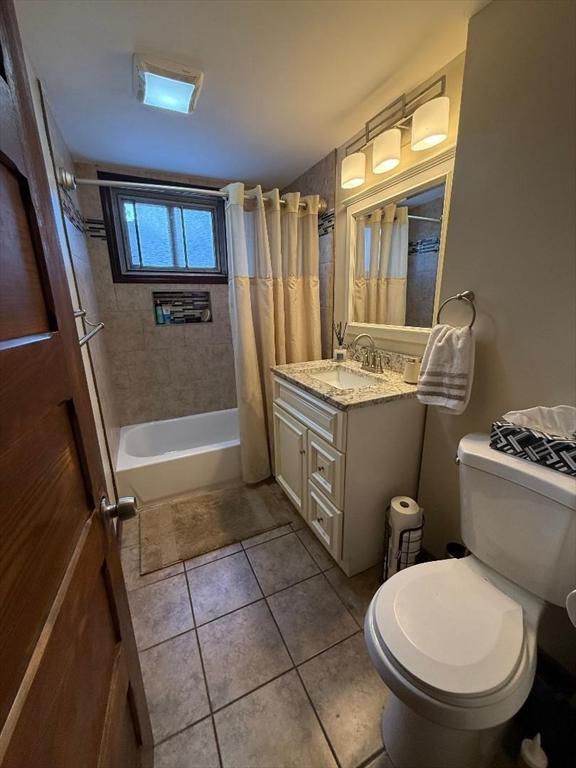 bathroom featuring tile patterned floors, shower / bath combo with shower curtain, and vanity