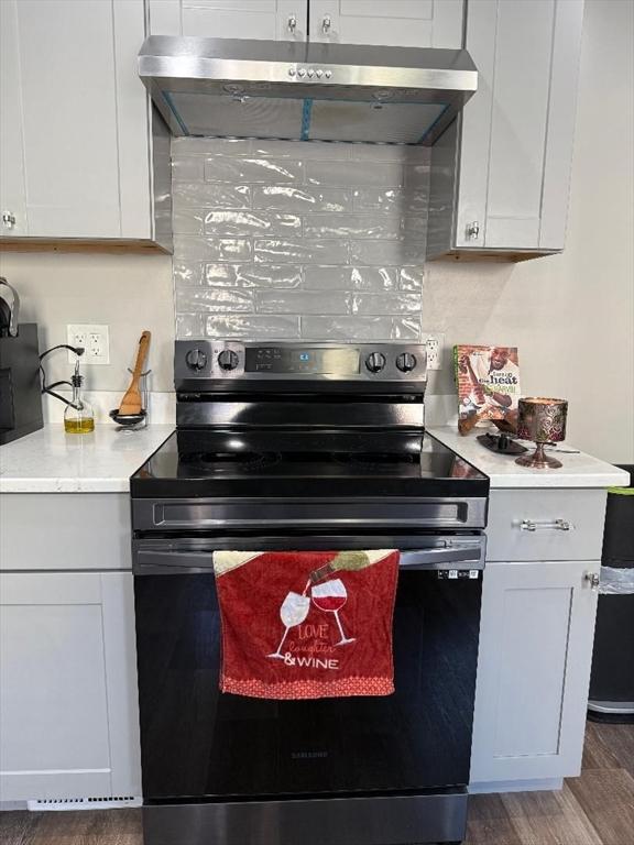 kitchen featuring white cabinetry, wood-type flooring, backsplash, and stainless steel electric range