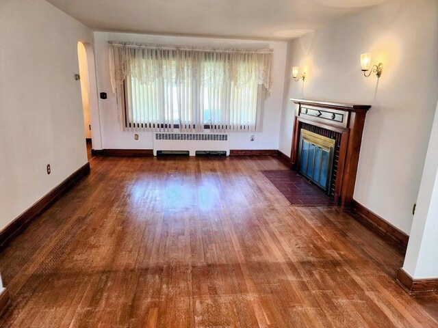 55 Kilburn St, Revere, MA 02151 - unfurnished living room with baseboards, radiator heating unit, wood finished floors, and a fireplace