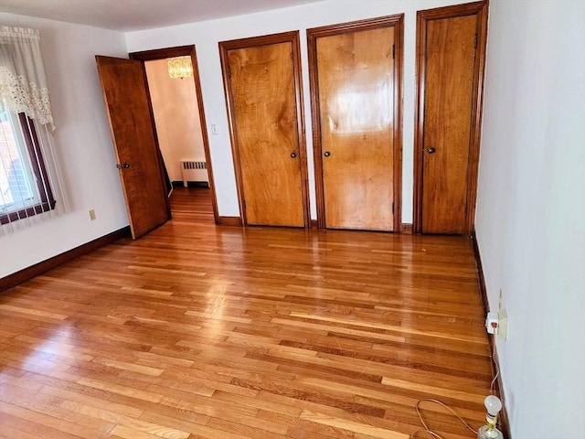 55 Kilburn St, Revere, MA 02151 - unfurnished bedroom with baseboards, radiator heating unit, multiple closets, and light wood-type flooring