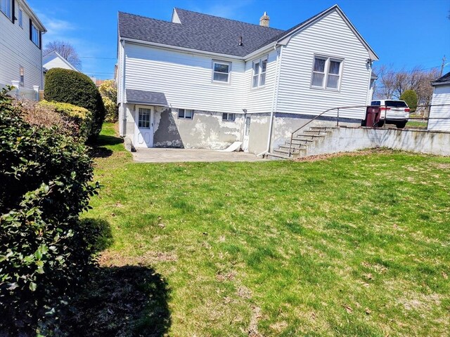 55 Kilburn St, Revere, MA 02151 - back of property featuring a shingled roof, a patio area, a lawn, stairs, and a chimney