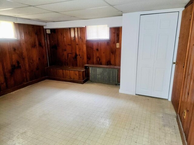 55 Kilburn St, Revere, MA 02151 - below grade area with tile patterned floors, radiator heating unit, wooden walls, and a paneled ceiling