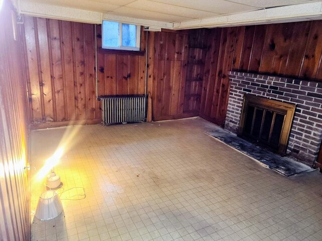 55 Kilburn St, Revere, MA 02151 - below grade area with wood walls, radiator heating unit, tile patterned floors, and a brick fireplace