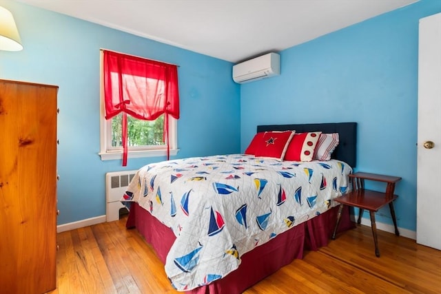 2 Olympia Ave, Woburn, MA 01801 - bedroom featuring radiator heating unit, a wall unit AC, wood-type flooring, and baseboards