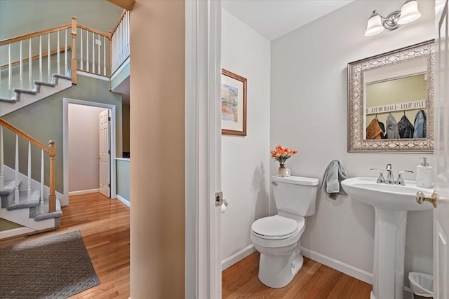 bathroom with wood finished floors, toilet, baseboards, and a sink
