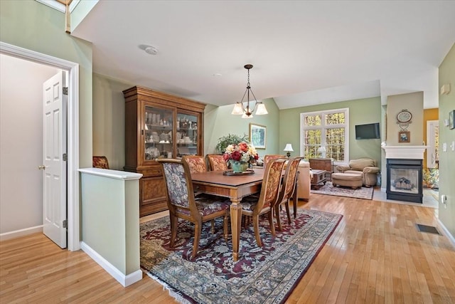 dining area with light wood-style flooring, a fireplace, and baseboards