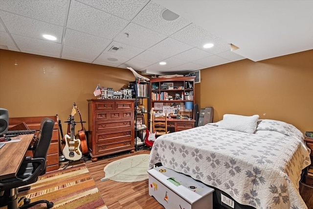 bedroom with wood finished floors, an office area, recessed lighting, and a drop ceiling