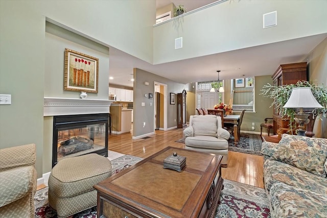 living room with light wood-type flooring, baseboards, and a multi sided fireplace