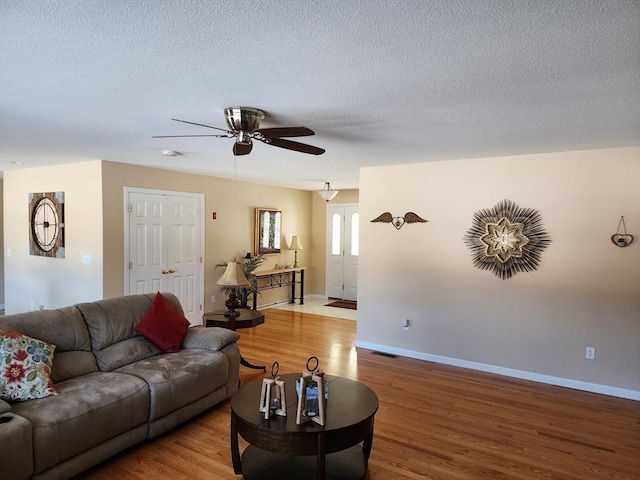 living room featuring ceiling fan, a textured ceiling, and light wood-type flooring