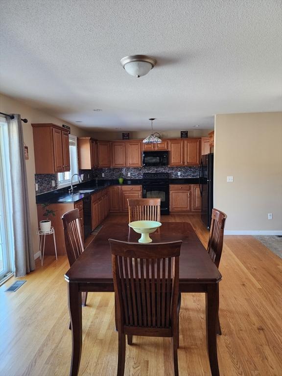 dining room with sink, light hardwood / wood-style floors, and a textured ceiling