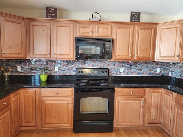 kitchen with backsplash, black appliances, dark stone counters, and light wood-type flooring