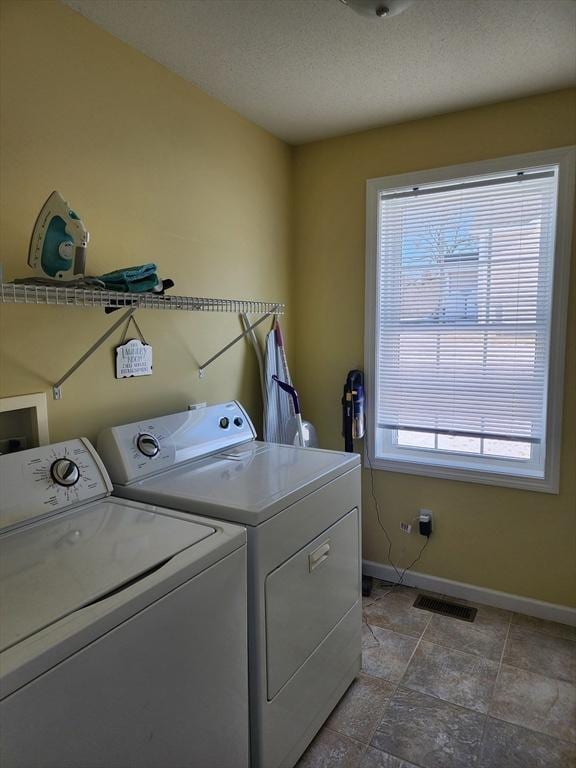 clothes washing area featuring washing machine and clothes dryer and a textured ceiling