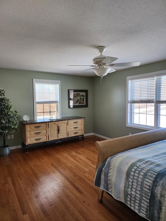 bedroom featuring ceiling fan, dark hardwood / wood-style floors, and a textured ceiling