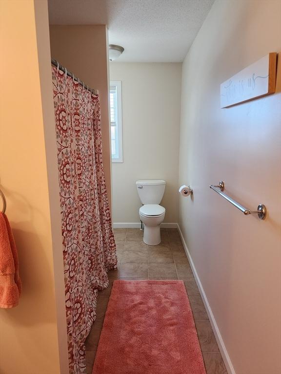 bathroom with tile patterned floors, a textured ceiling, and toilet