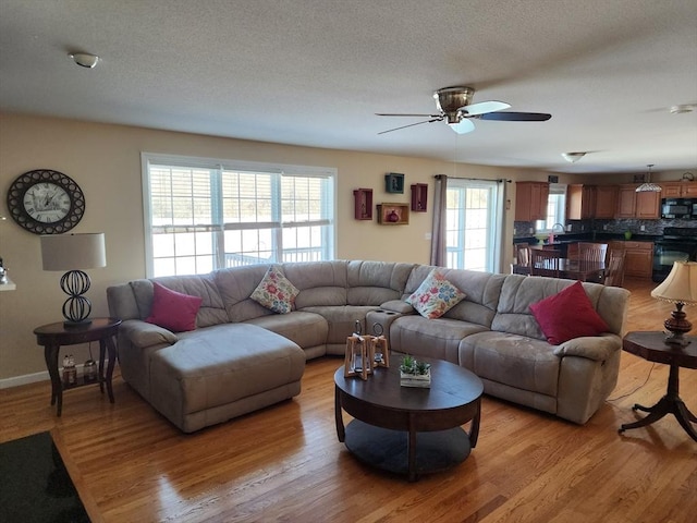 living room with ceiling fan, light hardwood / wood-style floors, sink, and a textured ceiling