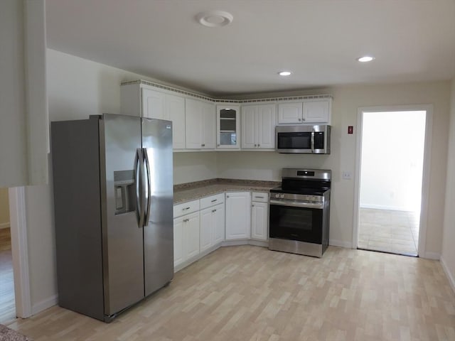 130 Fuller Rd, Barnstable, MA 02632 - kitchen featuring appliances with stainless steel finishes, light wood-type flooring, white cabinetry, glass insert cabinets, and baseboards
