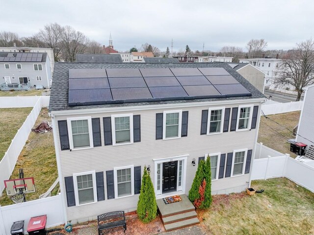 101 Bellevue Ave, Brockton, MA 02302 - view of front of home featuring roof mounted solar panels, roof with shingles, a fenced backyard, and a front yard