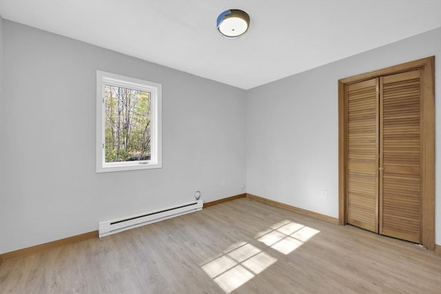 unfurnished bedroom featuring baseboards, a baseboard radiator, a closet, and light wood-style floors