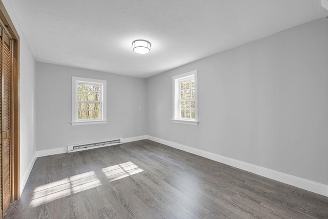 interior space with baseboards, a baseboard radiator, dark wood finished floors, and plenty of natural light