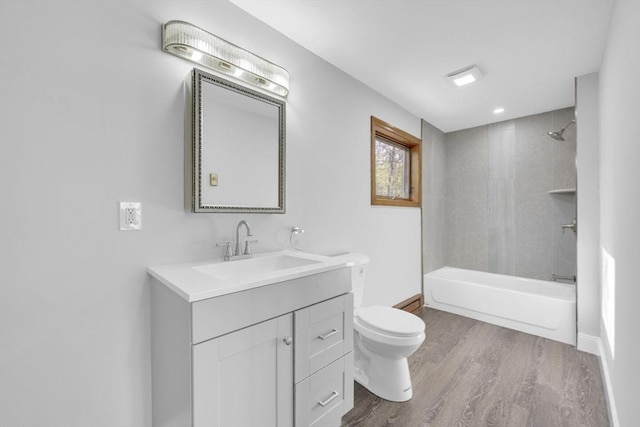 bathroom featuring toilet, wood finished floors, washtub / shower combination, baseboards, and vanity