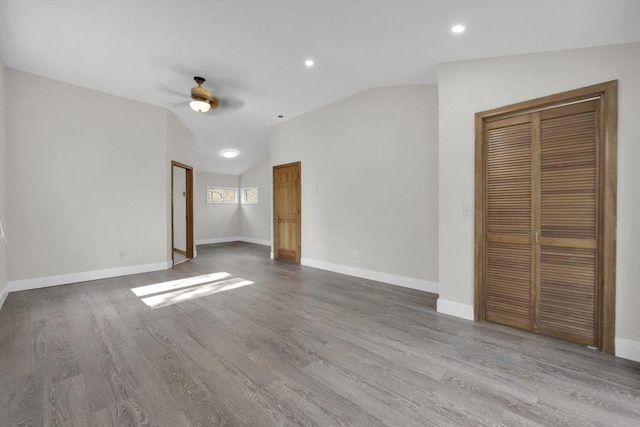 unfurnished bedroom with vaulted ceiling, baseboards, and wood finished floors