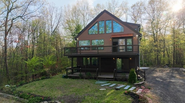 rear view of house featuring a yard, a wooden deck, and a forest view