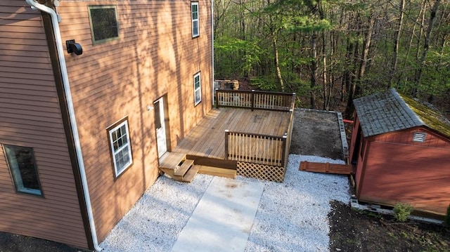 wooden deck featuring an outdoor structure, a forest view, and a shed