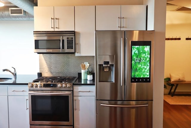 kitchen with sink, dark wood-type flooring, appliances with stainless steel finishes, backsplash, and white cabinets