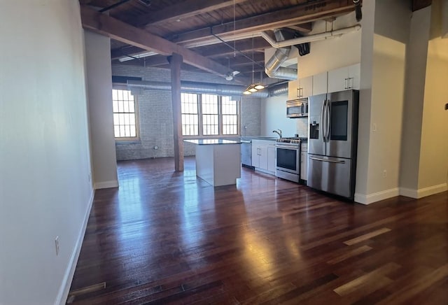 kitchen with stainless steel appliances, brick wall, white cabinets, and dark hardwood / wood-style flooring