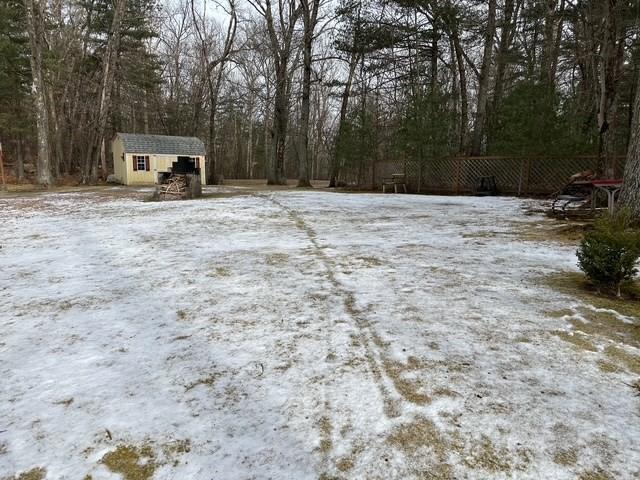 yard covered in snow with a storage shed