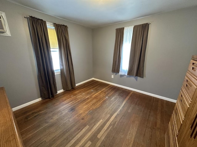 spare room featuring a wall mounted air conditioner, plenty of natural light, and dark hardwood / wood-style floors