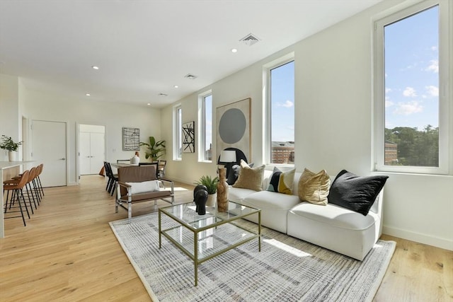 living room featuring light wood-type flooring, baseboards, and recessed lighting