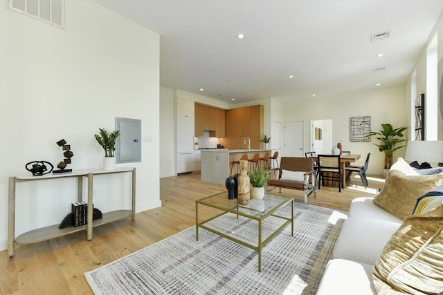 living room with light wood-style flooring, electric panel, visible vents, and recessed lighting