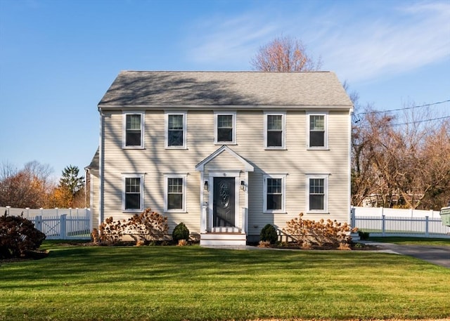 colonial inspired home featuring a front yard and fence