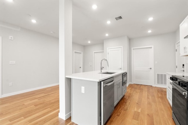 kitchen featuring light countertops, a kitchen island with sink, a sink, oven, and dishwasher