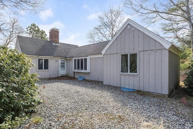 rear view of house featuring a chimney, board and batten siding, and a shingled roof